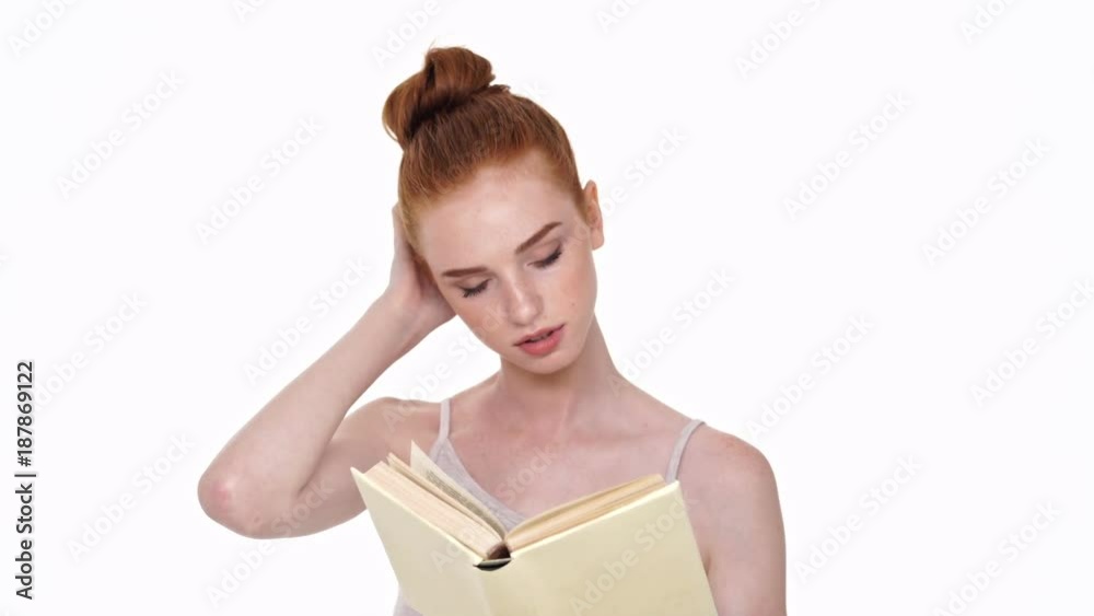 Concentrated redhead young lady isolated over white wall background reading book Concentrated redhead young lady isolated over white wall background reading book