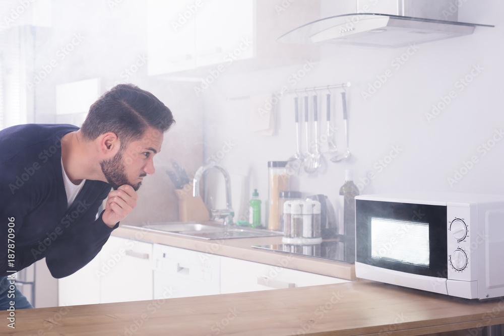 Man Spraying Fire Extinguisher On Microwave Oven Man Spraying Fire Extinguisher On Microwave Oven