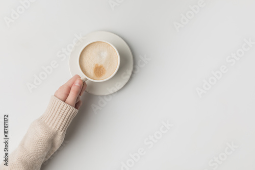 cropped view of woman holding cup of coffee in hand on white background