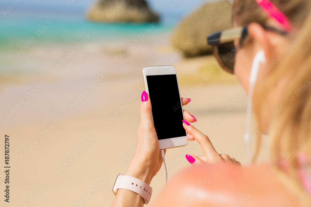 Fotografie Woman using smartphone on the beach
