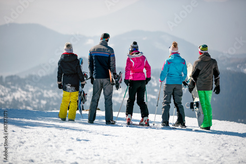 snowboarders enjoy the snow-white scenery of mountains and forests of the mountain top. Back view