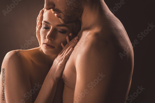 naked tender couple embracing with closed eyes, on brown