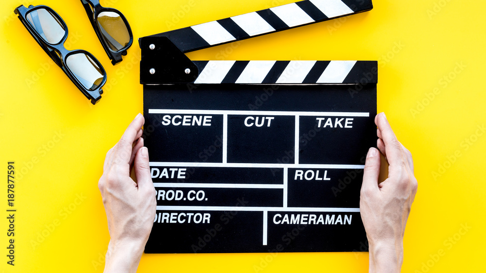 Filmmaker accessories. Clapperboard and glasses on yellow backgr
