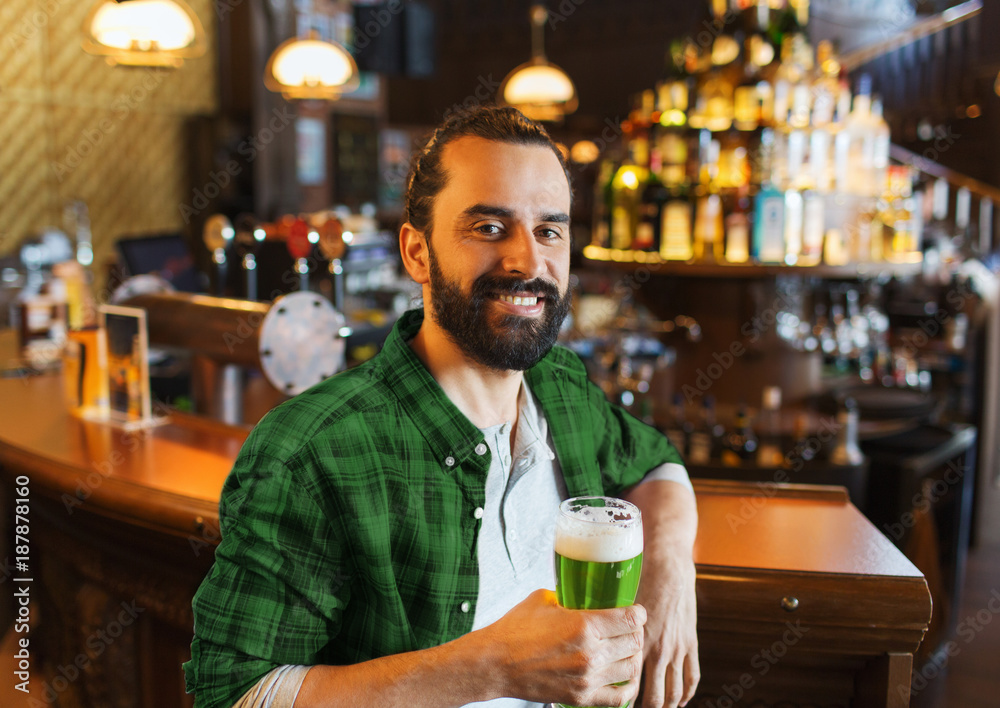 happy man drinking green beer at bar or pub
