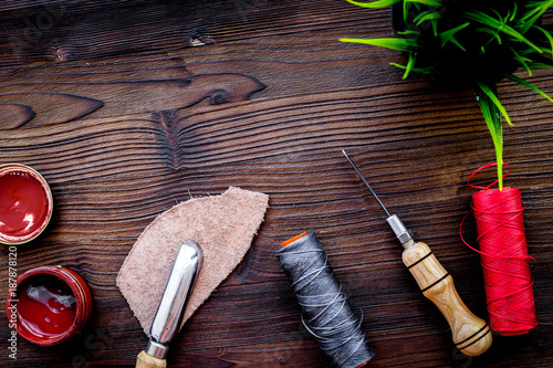 Leather craft. Tanner's tools on dark wooden table background to