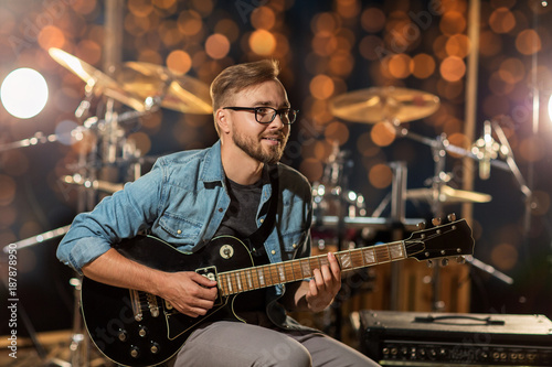 Fotografiet musician playing guitar at studio over lights