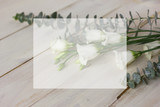 The flowers eustoma and eucalyptus on White wooden background. White square for your design