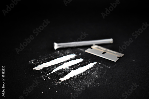 Cocaine line on a black background. Drugs still life. Drug, blade and snort tube. Drug accessories