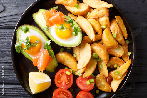 Avocado stuffed with eggs and salmon, fresh tomatoes and fried potato wedges close-up. horizontal top view