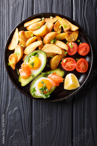 crockpot avocado stuffed with eggs and salmon, tomatoes and potato close-up on a plate. Vertical top view