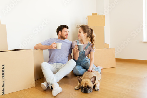 happy couple with boxes and dog moving to new home