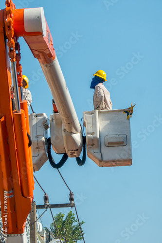 The ingineer machanic are looking to wire during fixing by using crane with the light blue sky background. photo