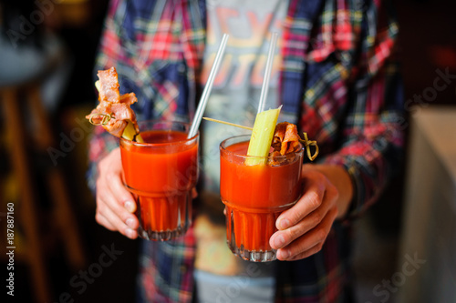 guy is holding two glasses of alcoholic cocktail Bloody Mary photo