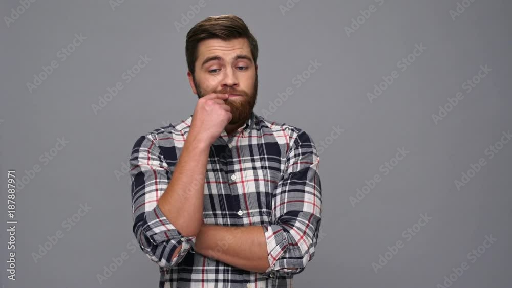 Thoughtful bearded man in shirt looking around over gray background Thoughtful bearded man in shirt looking around over gray background