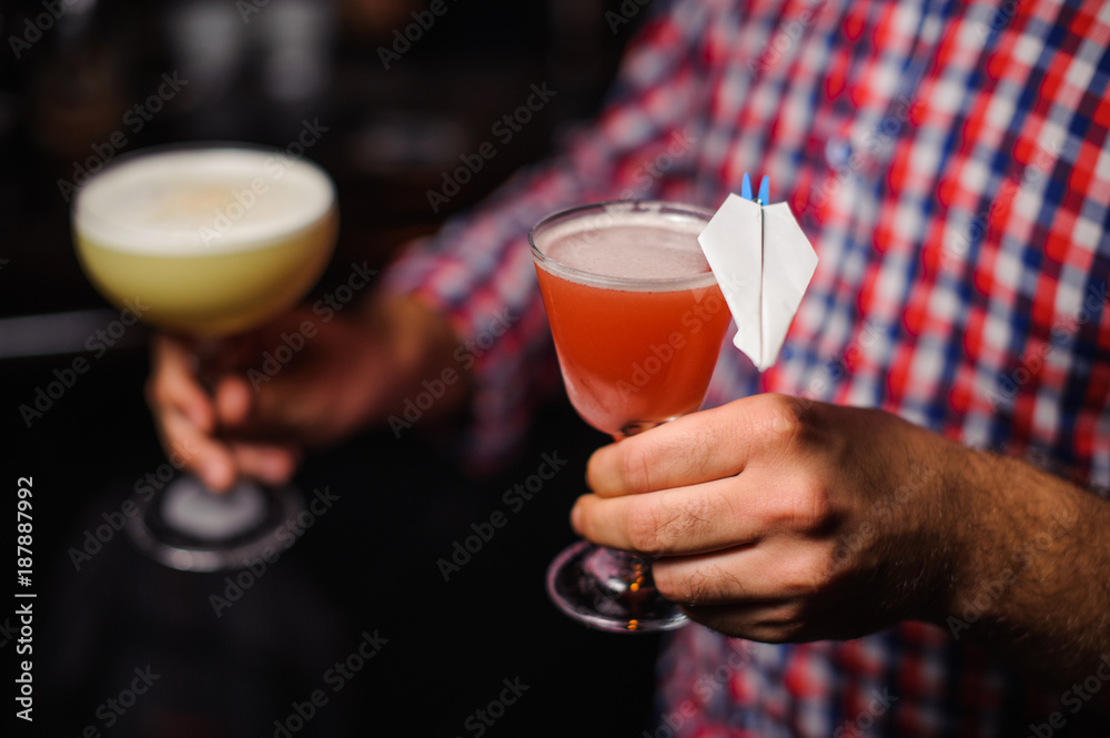 man holds two alcoholic cocktails of yellow and red colour man holds two alcoholic cocktails of yellow and red colour