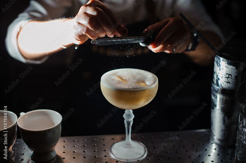 barman prepares an alcohol cocktail sour mix, adding powdered sugar