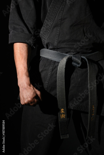Closeup of male karate fighter hands in black kimono and with a black belt
