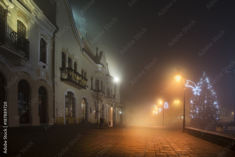 Town in the night in fog with christmas decoration