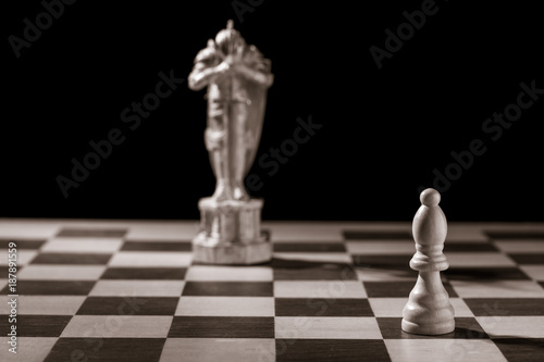 Classic white bishop and the same chess piece in the form of medieval figure on the background