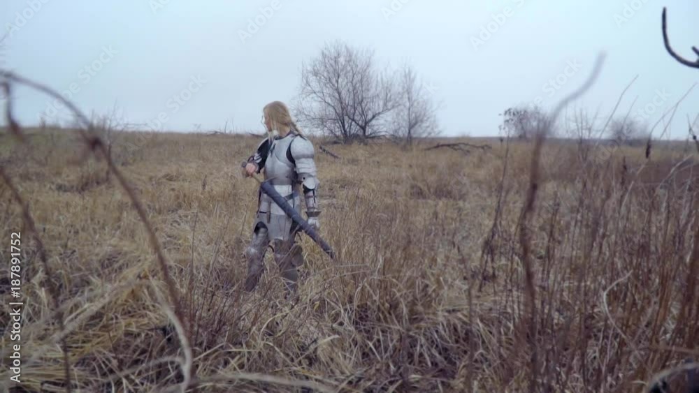 Rollback of the camera from a blonde in a medieval armor and a sword at the waist that looks around Rollback of the camera from a blonde in a medieval armor and a sword at the waist that looks around