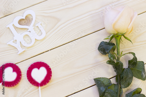 Concept of St.Valentine's Day, Love, Anniversary, Wedding with a pale cream rose, I love you inscription and decorations, natural wooden background, top view