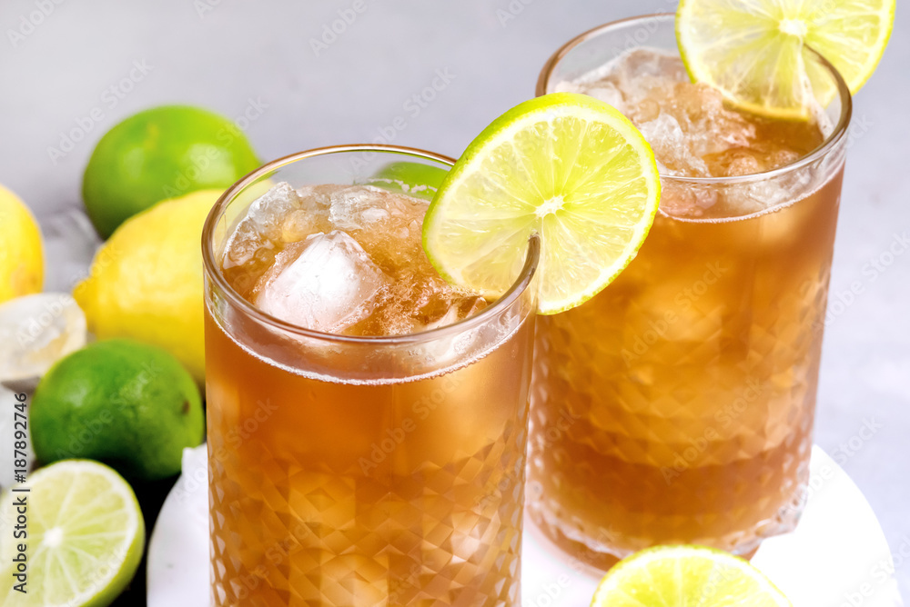 Glass of Tsasty Ice Tea with Ice Cubes and Citrus Cold Summ er Beverage Wooden Squeezer and Raw Lemons and Limes on Background Close Up Glass of Tsasty Ice Tea with Ice Cubes and Citrus Cold Summ er Beverage Wooden Squeezer and Raw Lemons and Limes on Background Close Up