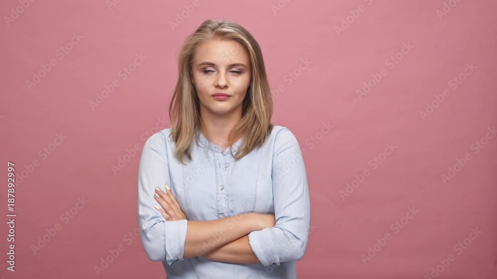 Displeased blonde woman in shirt disagree with something over pink background Displeased blonde woman in shirt disagree with something over pink background