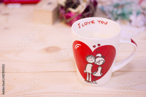 Concept of St.Valentine's Day, Love, Anniversary, Wedding with a white porcelian mug decorated with a heart image and I Love You inscription on a wooden table photo