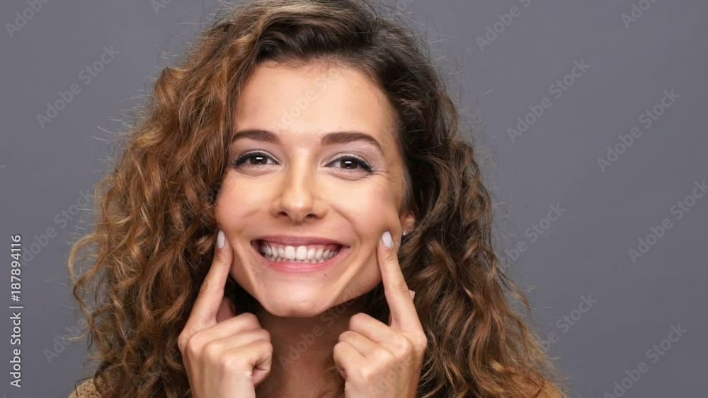 Close up view of pretty woman in sweater smiles at the camera over purple background Close up view of pretty woman in sweater smiles at the camera over purple background