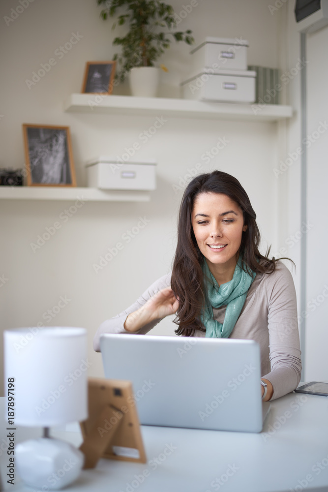 Woman using laptop at home office.