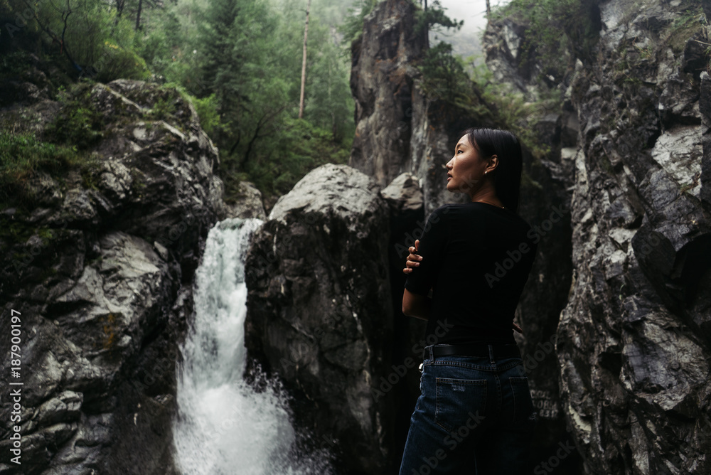 Girl in blue jeans in front of big waterfall
