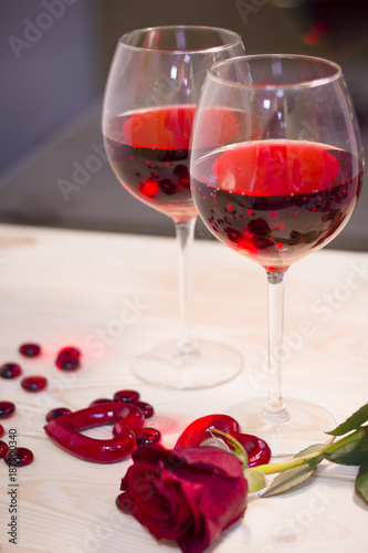 The concept of Love, Wedding, Proposal, Anniversary. A romantic evening with two glasses of red wine and a beautiful red velvet rose. Dark blurred background