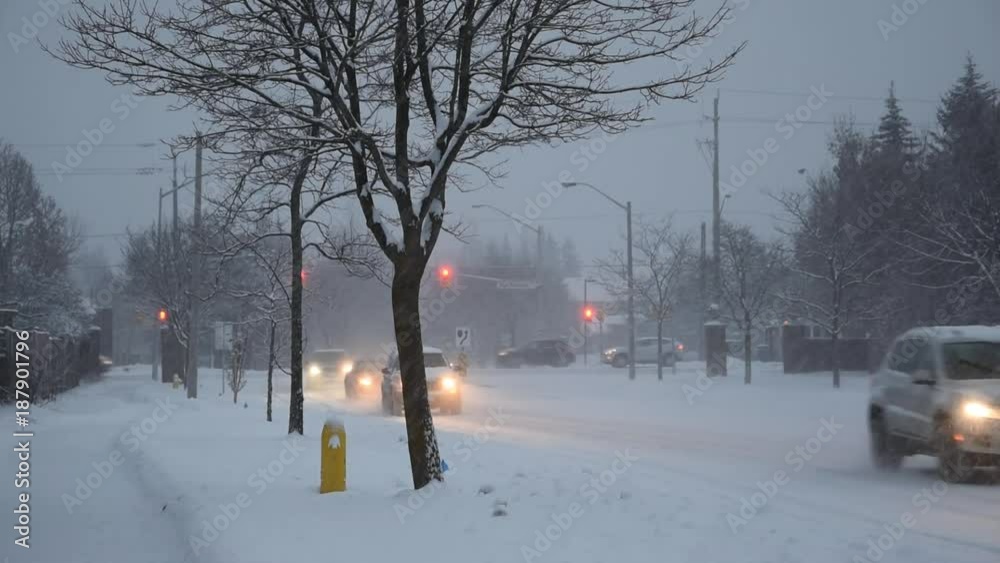 Snowfall in the city with cars, street lamps and traffic light Snowfall in the city with cars, street lamps and traffic light