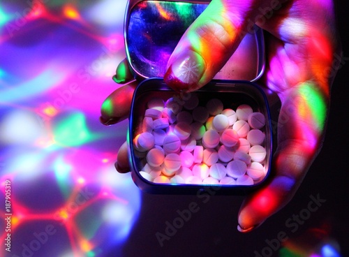 A young woman with nice nails offers ecstasy on a disco. photo