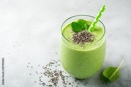Vegetarian healthy green smoothie from avocado, spinach leaves, apple and chia seeds on gray concrete background. Selective focus. Space for text. photo