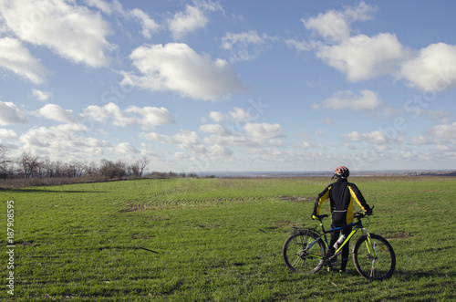 man with a bicycle on a green field