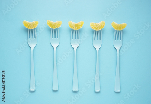 Yammy forks / Creative concept photo of forks with tangerines on blue background.