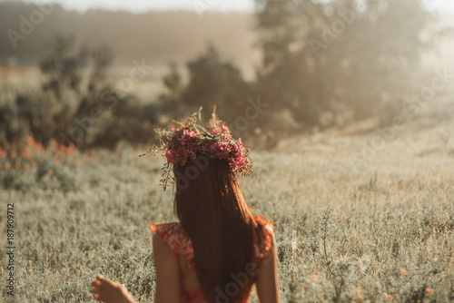 Happy young woman in a wreath from wildflowers and grass. Cute girl with summer flowers, closeup photo