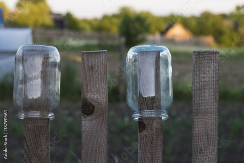 Two glass jars drying on the fence in the backyard