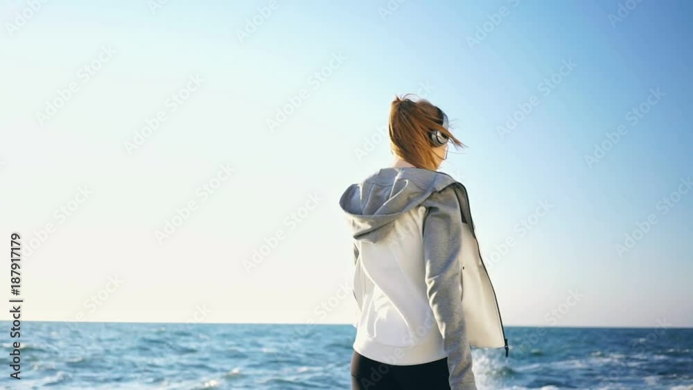 Pretty brunette sports woman in headphones walking at the seaside Pretty brunette sports woman in headphones walking at the seaside