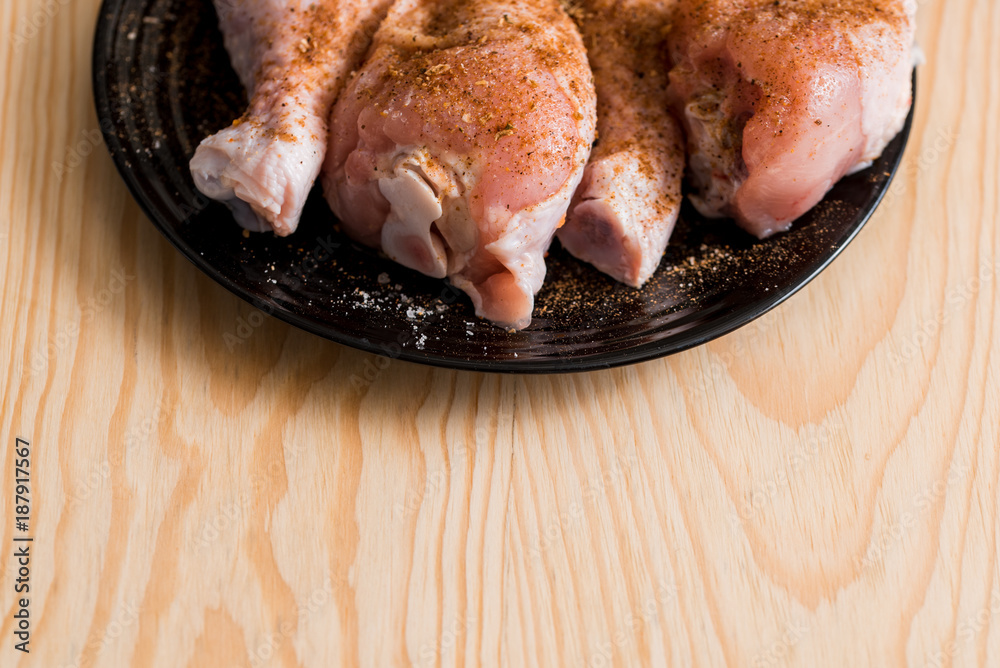 Preparation of tibia chicken, chicken legs on a black plate, wooden  background, spices and salt. Copy place for inscription Stock Photo | Adobe  Stock
