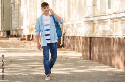 Trendy teenage boy talking on mobile phone outdoors