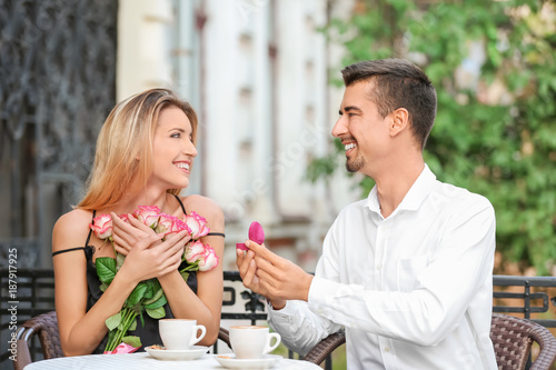 Young man with engagement ring making proposal of marriage to his girlfriend in cafe