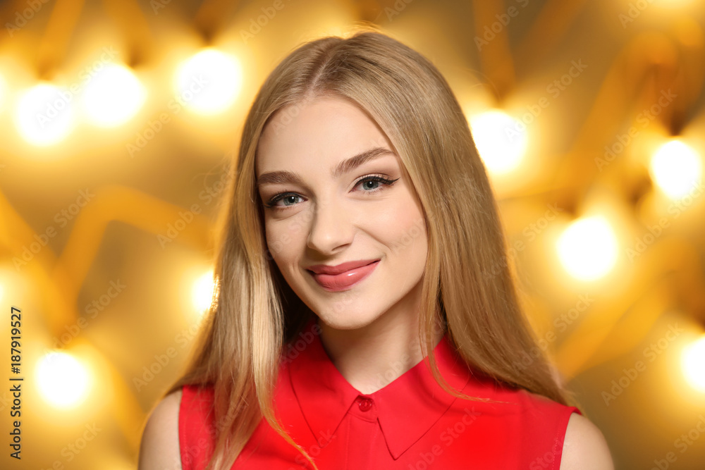 Portrait of young beautiful smiling woman on blurred lights background