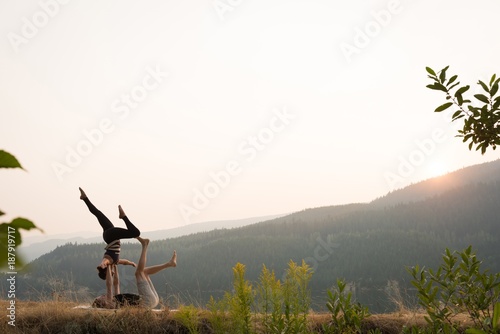 Sporty couple practicing acro yoga in a lush green ground photo