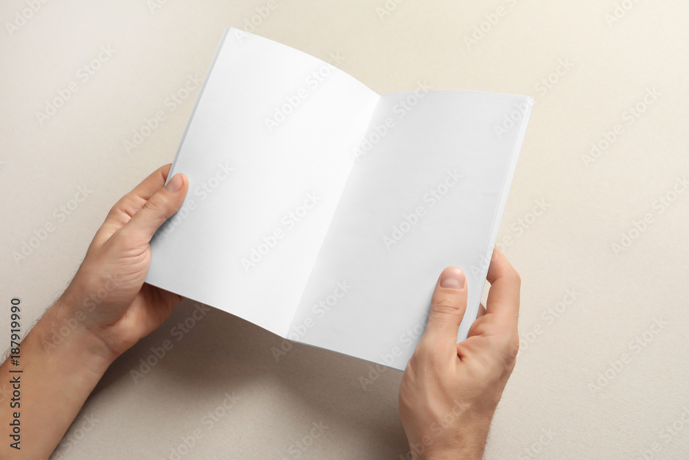 Man holding brochure with blank pages on light background. Mock up for design Man holding brochure with blank pages on light background. Mock up for design