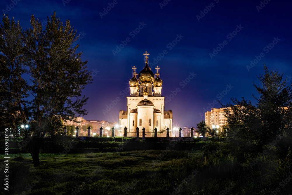 A beautiful Orthodox cathedral surrounded by trees at night brightly illuminated. Concept: religion.