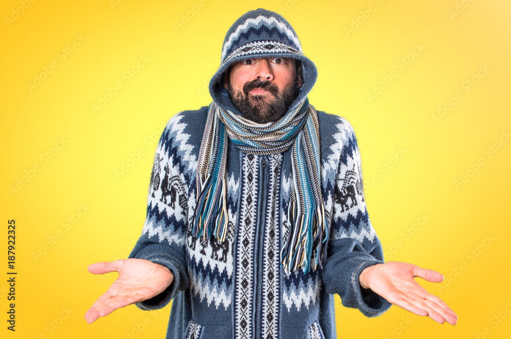 Man with winter clothes making unimportant gesture on colorful background Man with winter clothes making unimportant gesture on colorful background