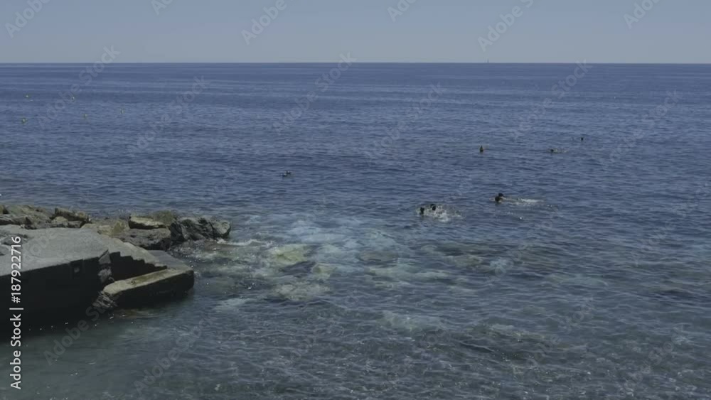 Small group of people swimming in very clear water near a stone cliff. Small group of people swimming in very clear water near a stone cliff.
