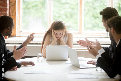 Male colleagues pointing fingers at upset female boss on meeting, tired sad woman leader experiencing gender discrimination at work, businessmen blaming bullying depressed businesswoman for mistake